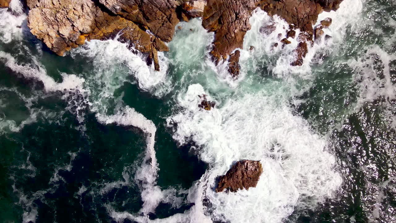 de arriba hacia abajo de las olas del océano surgiendo contra la escarpada costa rocosa