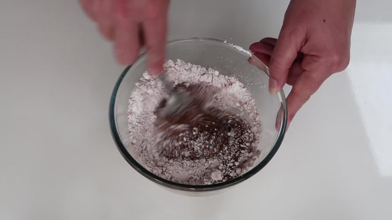 Mixing cocoa and icing sugar with butter and water