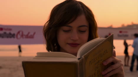 woman reading a book on the beach at sunset