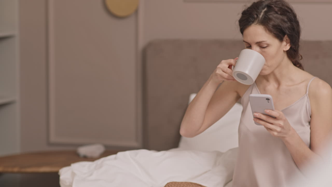 Donna che si rilassa a letto con il caffè e il telefono