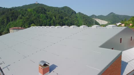 flying up beside big sports hall with ladder and grey insulation panels on rooftop