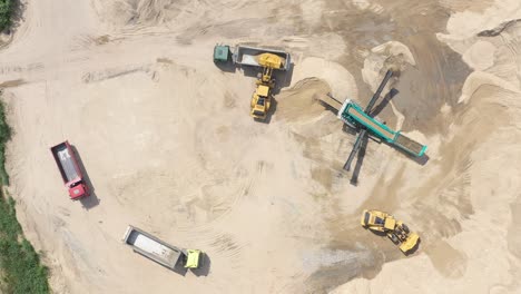 vista aérea superior de la excavadora cargando arena en un camión volquete vacío en una cantera al aire libre