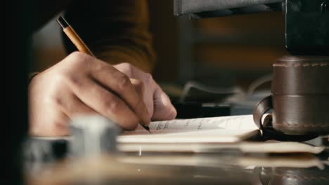 a man's hand writes notes in a notebook