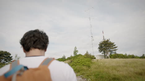 Camera-tracking-hiker-from-behind-who-is-ealking-towards-the-high-antenna-at-the-top-of-mountain-Trstelj