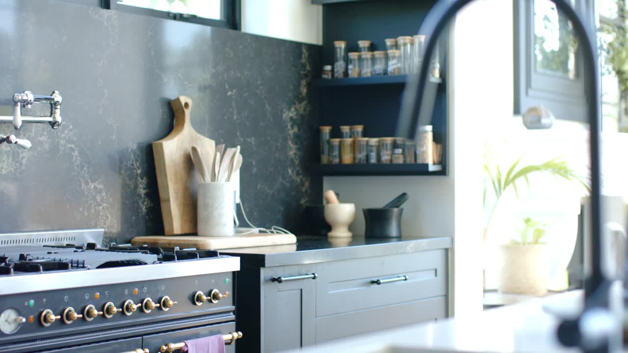Camera is panning left and is racking focus on island, revealing black faucet, tray, spice rack