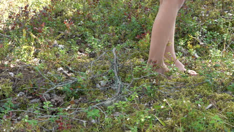 Young-girl-walking-barefoot-on-mossy-forest-floor,-static-view