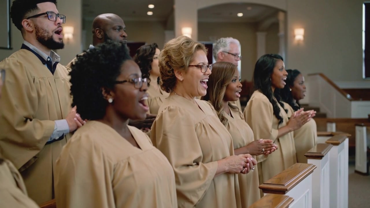 Singing church choir growing while worship song starting in sanctuary pew rail, clapping tan robes