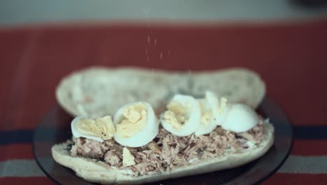 Salting-an-egg-with-tuna-fish-sandwich,-white-bread-toast,-slow-motion-120-fps