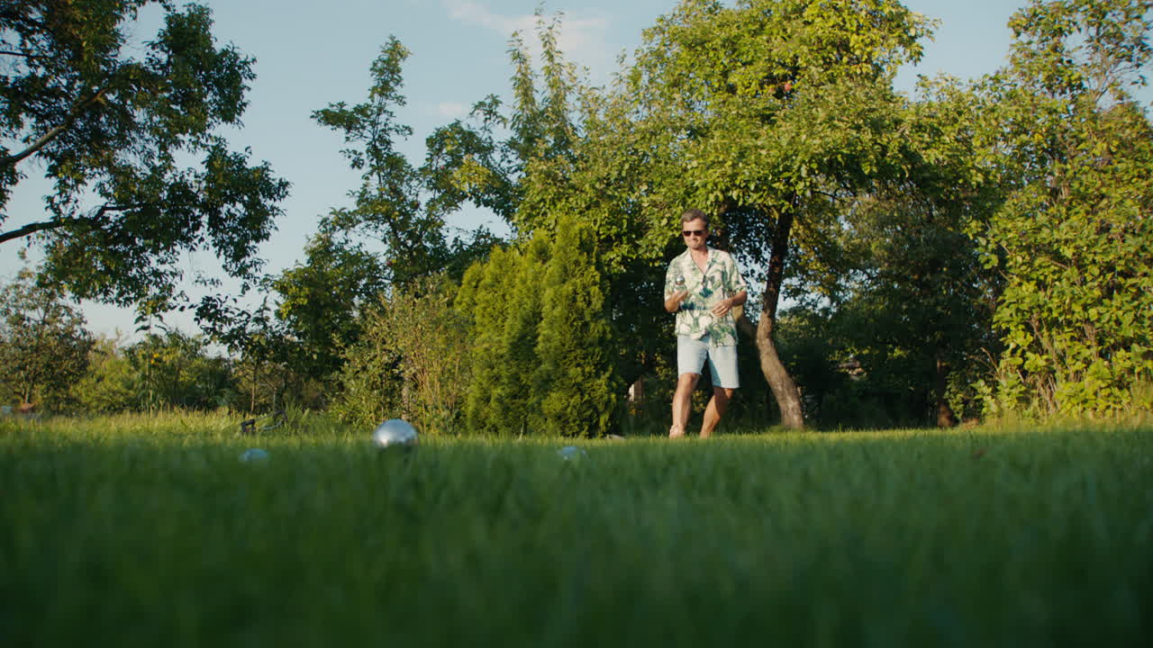 Man playing petanque in a garden on a sunny day