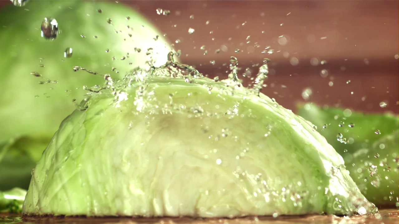 Metà di cavolo verde fresco con schizzi d'acqua al rallentatore