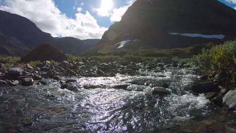 a cold stream on a sunny day next to some big mountains. close to silverfallet and kebnekaise, sweden.