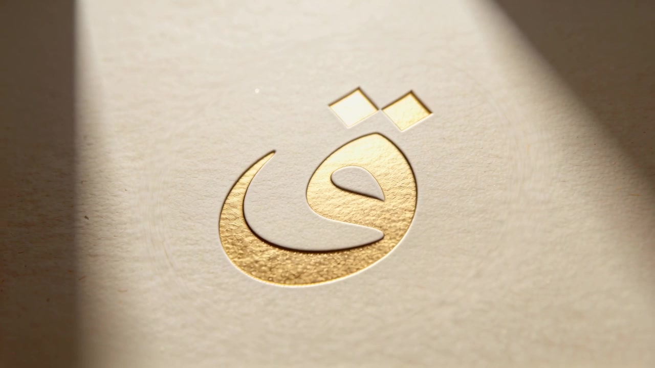 Sweeping diagonal beam revealing gold foil Arabic glyph on cream paper desk exposing embossed edge