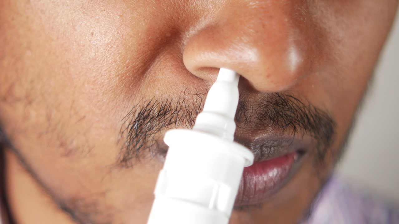 A close-up of a person using a nasal spray