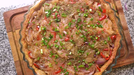 vista superior de la tarta de cebolla cruda con pimiento rojo, cebolletas, especias y hierbas