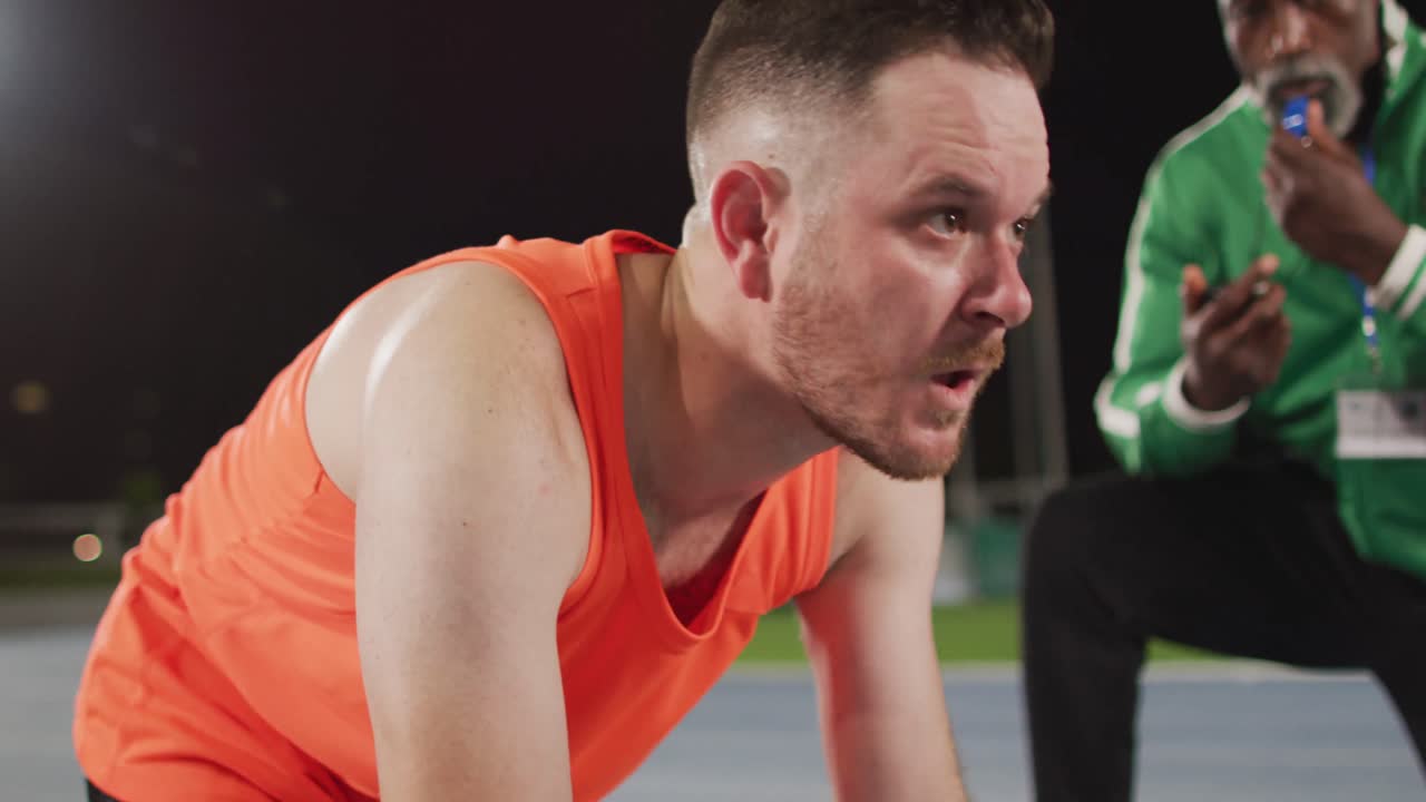 다양한 남성 코치와 남성 선수가 달리기를 시작할 준비를 하고 있습니다.