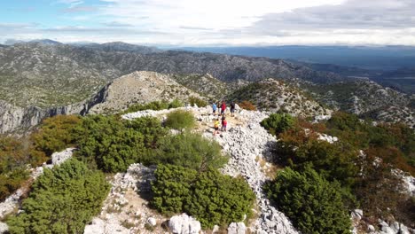 aerial pullback of hikers on mount st. ilija peak in croatia, rugged terrain and expansive mountain landscape