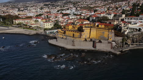 Toma-Aérea-En-Un-Círculo-Del-Fuerte-De-Madeira-En-La-Ciudad-De-Funchal-Y-Donde-Se-Pueden-Ver-Las-Numerosas-Casas-Y-Edificios-De-La-Costa