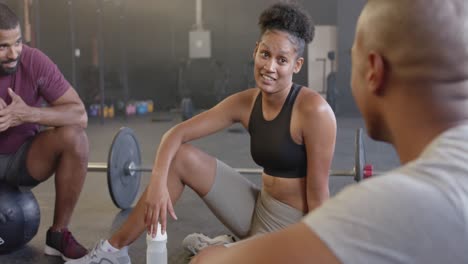 happy diverse group sitting and talking after training in fitness class at gym, in slow motion