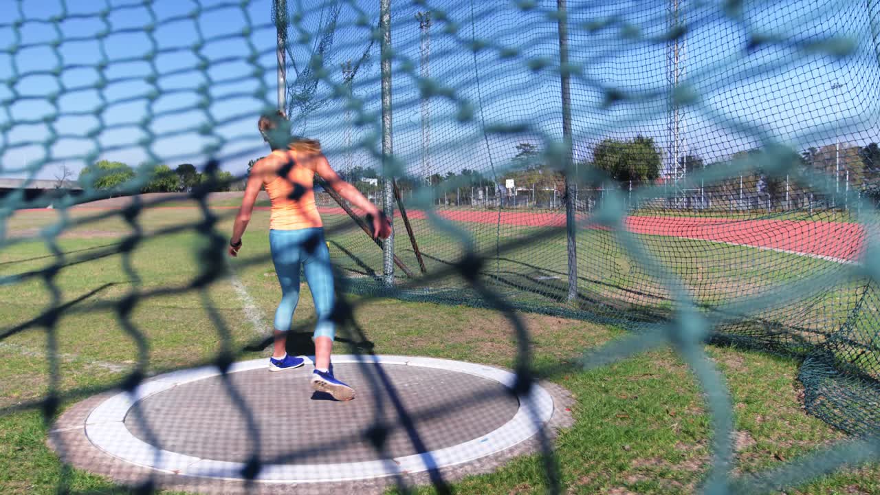카우카스 여성 선수가 스포츠 장소에서 디스크 던지기를 연습하고 있습니다.