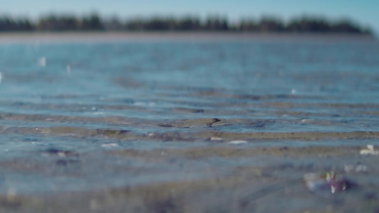 Shallow blue water ripples flowing gently over a sandy coastal beach