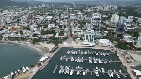 Panorámica-Aérea-Sobre-La-Ciudad-De-Santa-Marta-Colombia-Rodadero-Playa-Barcos-Horizonte-De-Destino-De-Viaje,-Establecimiento-De-Tiro