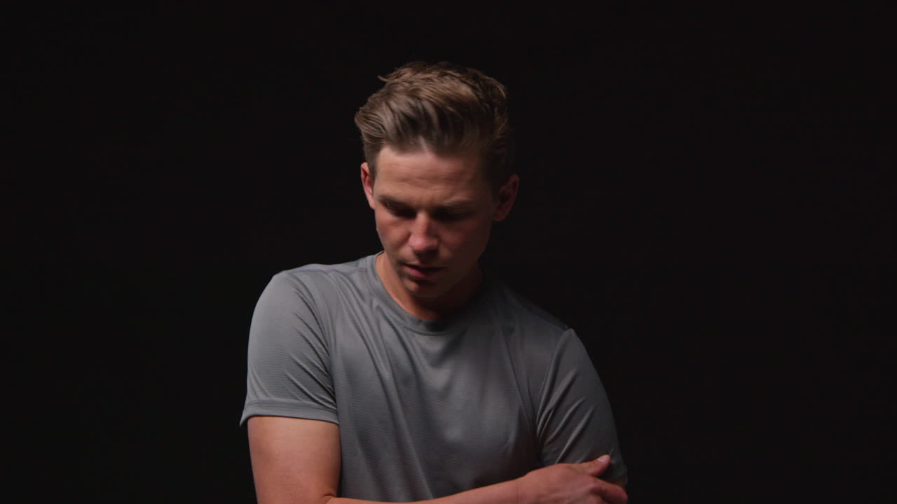 검은색 스튜디오 배경에 대한 스포츠 이벤트를 위해 심리적으로 준비하고 체육 의류를 착용하는 심각한 남성 운동 선수의 초상화