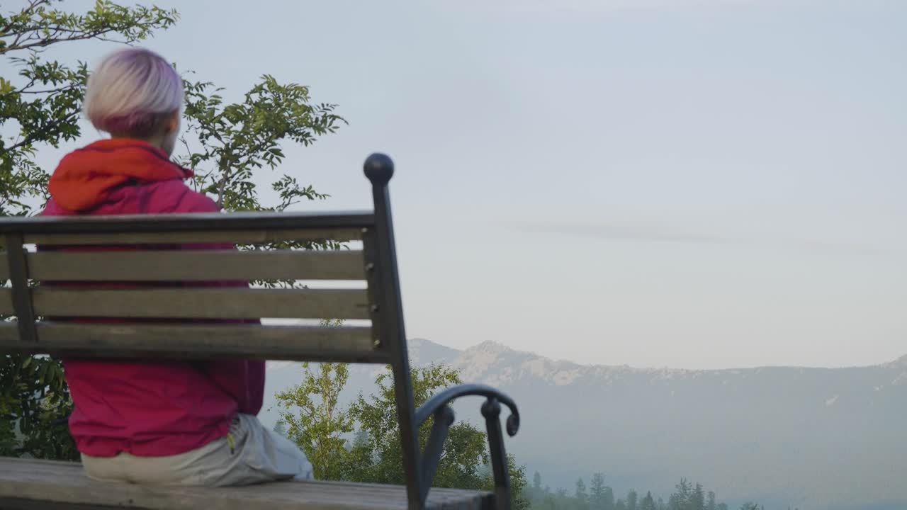 해가 뜨면 산의 풍경을 바라보는 벤치에 앉아 있는 여자