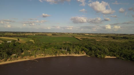 amplia toma aérea de la costa de fray bentos y campos agrícolas en segundo plano durante la puesta de sol en uruguay