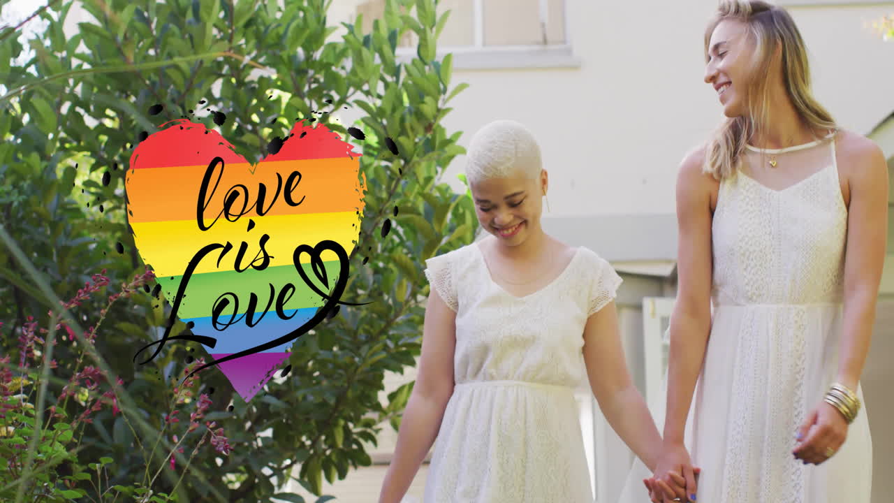Animation of rainbow heart with love is love text over diverse female married couple holding hands