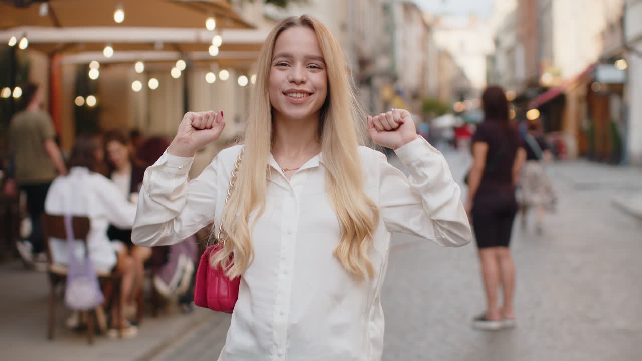 Young woman shouting celebrating success winning goal achievement good victory news in city street