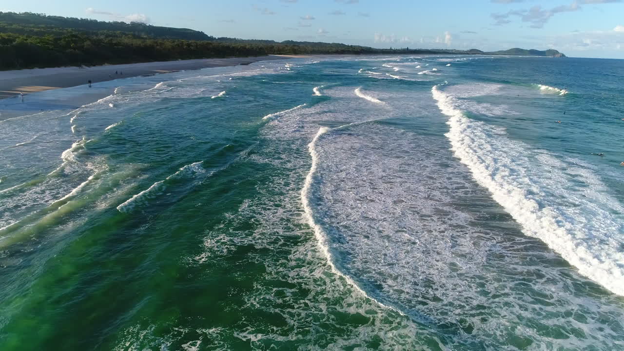 vuelo bajo sobre una playa increíble con olas repetitivas rompiendo contra la playa