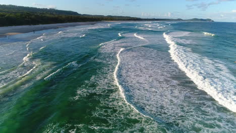 low fly over amazing beach with repetitive waves crashing up against the beach