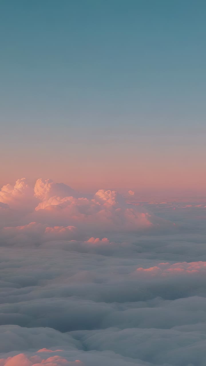 Vertical video: Drifting cloud deck with towers shifting with sunlight above horizon, pastel sky