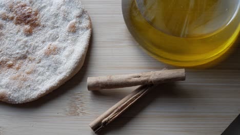 crispy torta de aceite with cinnamon sticks and olive oil on light wood surface