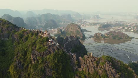 aerial drone flying towards a big limestone mountain with a dragon temple in vietnam