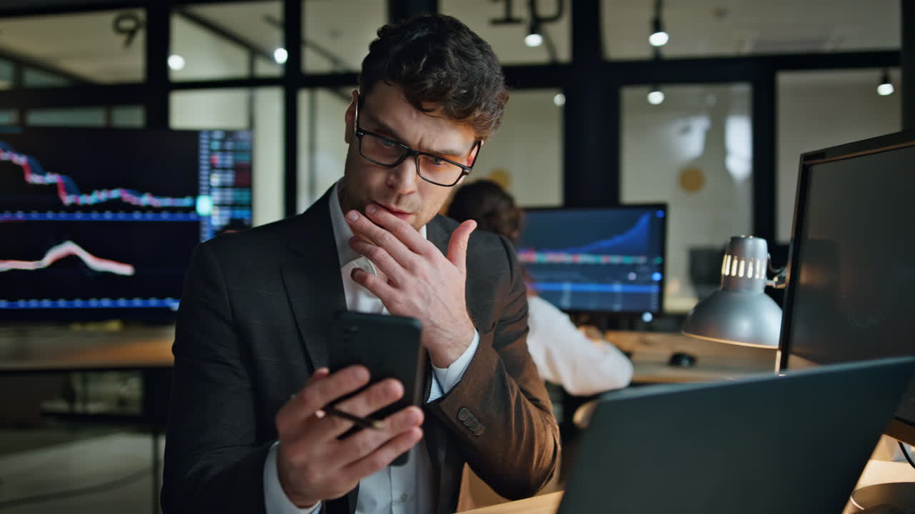 Stock trader holding smartphone work in office. Focused man professional check