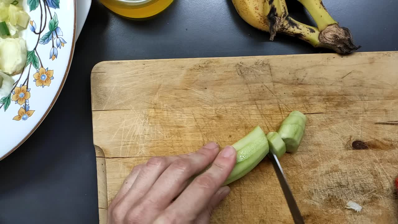 Food preparation cutting cucumber on a wood surface for salad