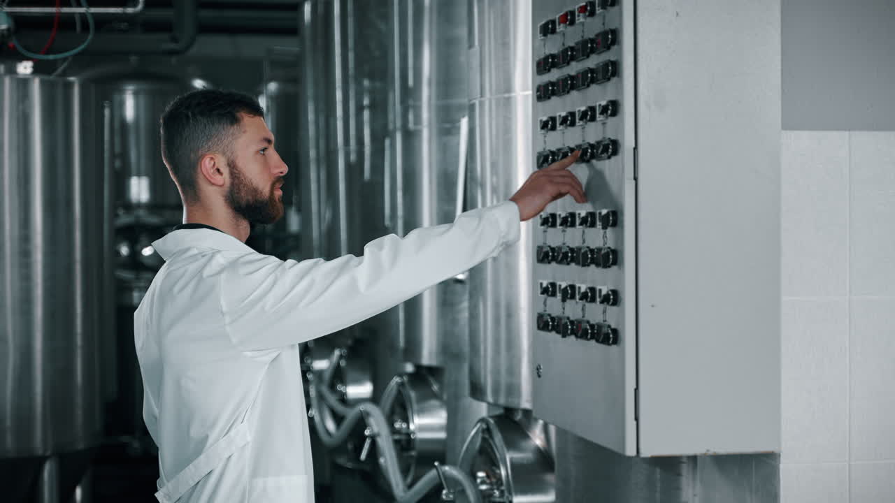 рабочий пивоваренного завода управляет панелью управления