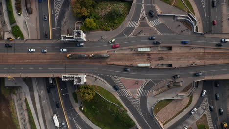 Aerial-birds-eye-overhead-top-down-view-of-traffic-on-wide-road-bridge-over-Vistula-river.-Tracking-on-tram-departing-from-tram-stop.-Warsaw,-Poland