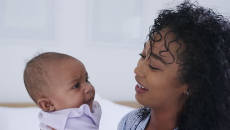 Loving-African-American-Mother-Wearing-Pyjamas-Playing-With-Baby-Daughter-In-Bedroom-At-Home