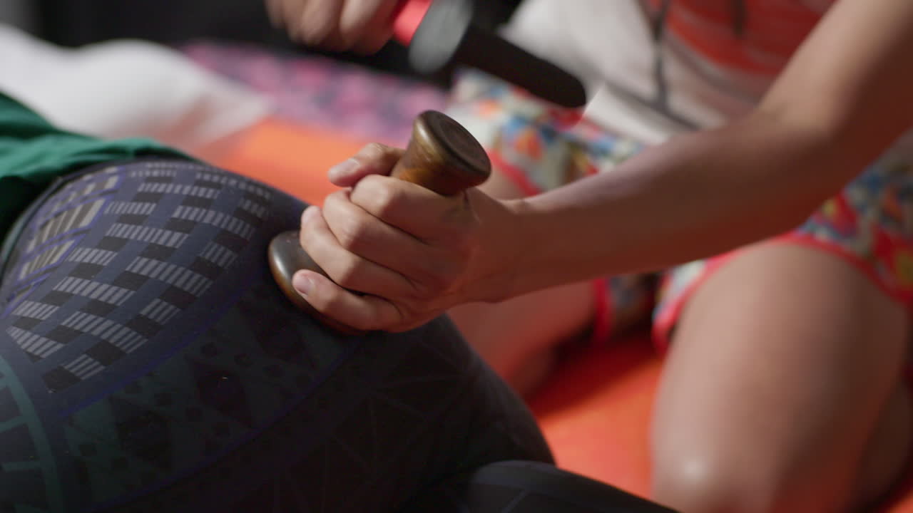 el masajista tailandés martilla la parte inferior de la espalda y los glúteos de una cliente femenina para romper la fascia