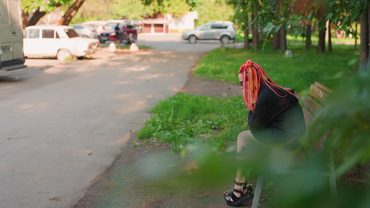 혼자 있는 여성, 화려한 머리 스타일을 한 독립적인 여성, 도시 공원에 홀로 서 있는 여성, 활기찬 드레드록을 한 외로운 여성이 도시 환경 속에서 조용히 멈춰 서 있어요.