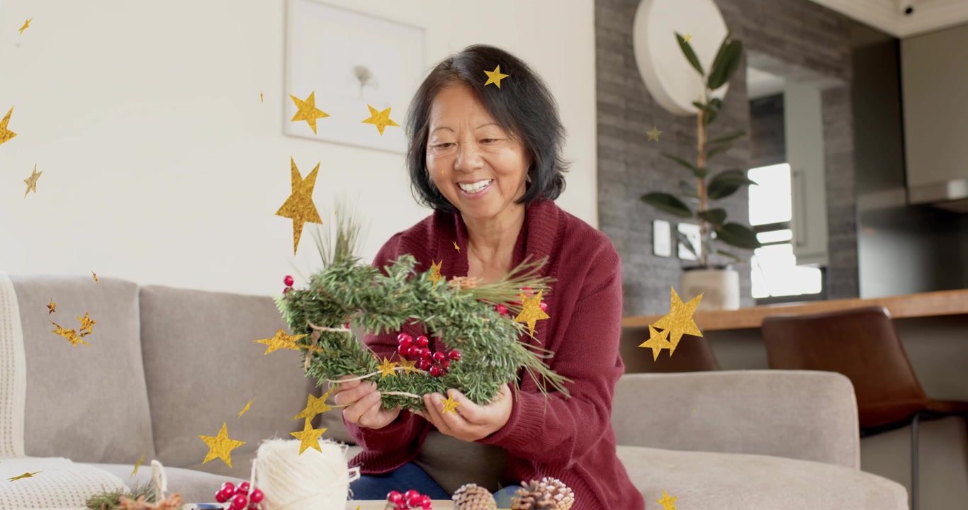 Mulher idosa inspecionando guirlanda com animações de estrelas, enrolando barbante, ajustando detalhes para decoração de casa.