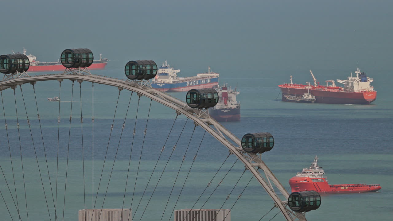 SINGAPORE - 5 MARCH 2025 : container ships waiting in the sea by singapore with observation ferris wheel in foreground