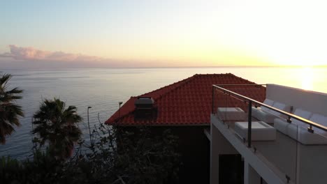 A drone shot going slowly over the perfectly still water of the infinity pool in a luxury hotel in Ponta do Sol in Madeira during a beautiful and warm sunset with the view over the ocean.