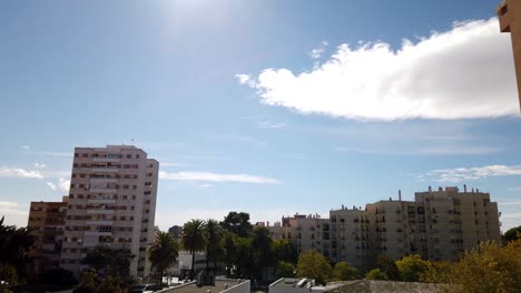 Timelapse-of-Bright-Sun-Dissipating-Wispy-Clouds-over-Tall-Apartment-Buildings