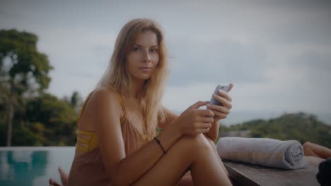 woman relaxing by the pool with her mobile phone
