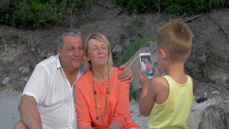 un niño tomando fotos de sus abuelos con un teléfono móvil