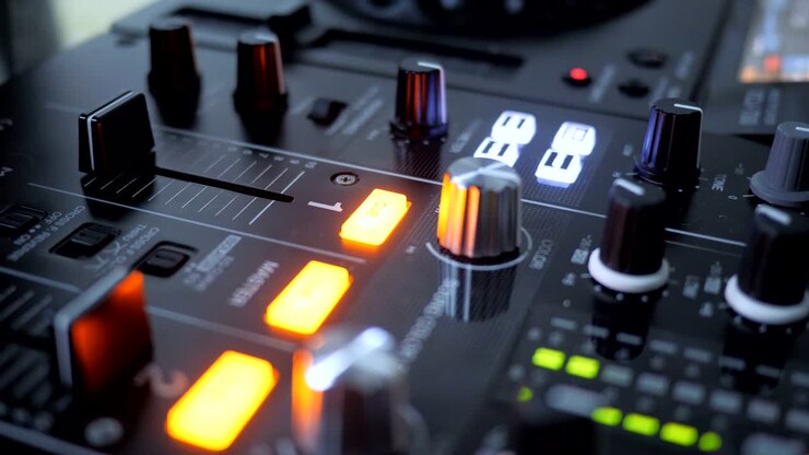 Primo piano di una mano che aumenta il volume di un mixer da DJ, muovendo il fader