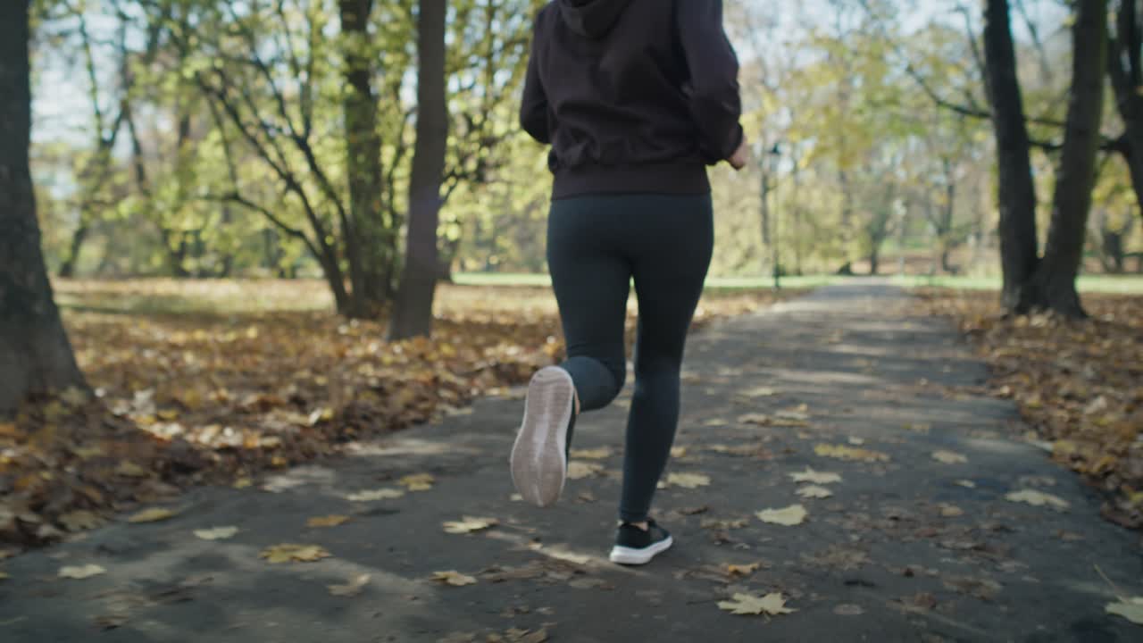 Handheld of low section of woman's legs jogging at the park